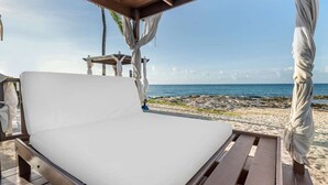 Een strandbed met uitzicht op de zee, een houten constructie en een strand op de achtergrond.