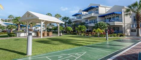 A courtyard with a shuffleboard court, outdoor seating, and a covered area.