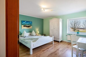 Quarto com cama, guarda-roupa, escrivaninha e janela com vista.