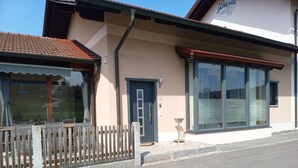 A building with a large window, a door, and a small outdoor table.