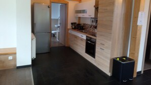 A kitchen with wooden cabinets, a refrigerator, a sink, and a coffee maker.