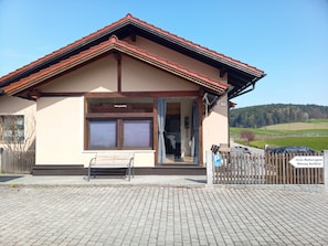 Un bâtiment doté d’un toit en pente, d’un banc à l’extérieur et d’une entrée pavée.