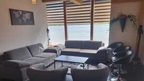 A modern living room with a grey sofa, two armchairs, a coffee table, and a view through large windows.