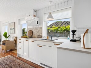 Een koelkast, een oven, een vaatwasser, kookgerei, borden en bestek