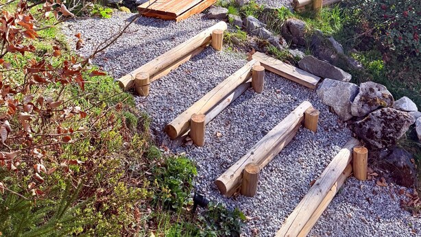 Een houten hutje met een gebogen dak, een deur en een klein terras.