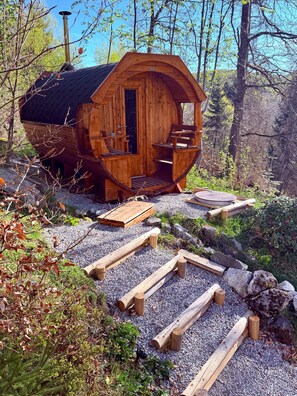 Uma cabana de madeira com telhado curvo, uma porta e um pequeno alpendre.