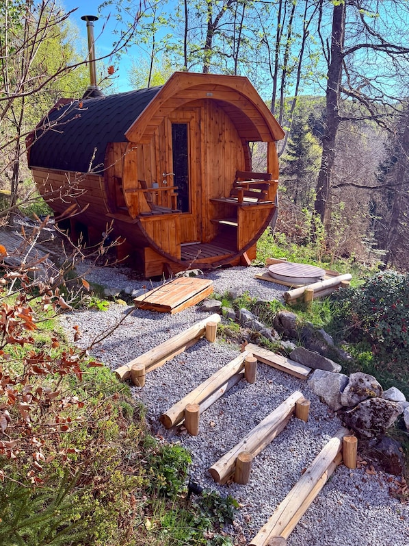 Una cabaña de madera con techo curvo, una puerta y un pequeño porche.
