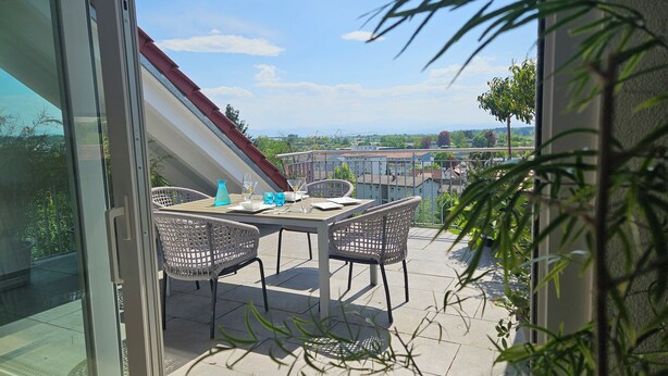 A balcony with a table set for two, overlooking a cityscape.
