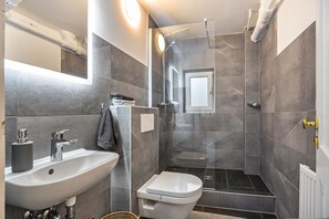 Un baño moderno con lavamanos, inodoro y ducha.