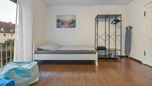 Un dormitorio con cama, un cuadro, un mueble metálico y vistas a edificios.
