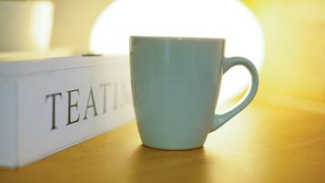 A light blue mug on a wooden surface next to a white box with the word 'TEA' visible.