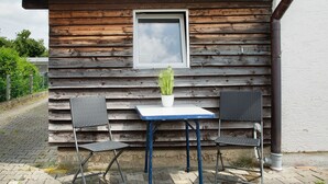 A wooden cabin with a window, a table, and two chairs. - Seelina Apartment in Perach – Quiet, Cozy & Close to Nature (Perach)