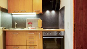 A kitchen with wooden cabinets, a stainless steel sink, a stove, and an oven. - Seelina Apartment in Perach – Quiet, Cozy & Close to Nature (Perach)