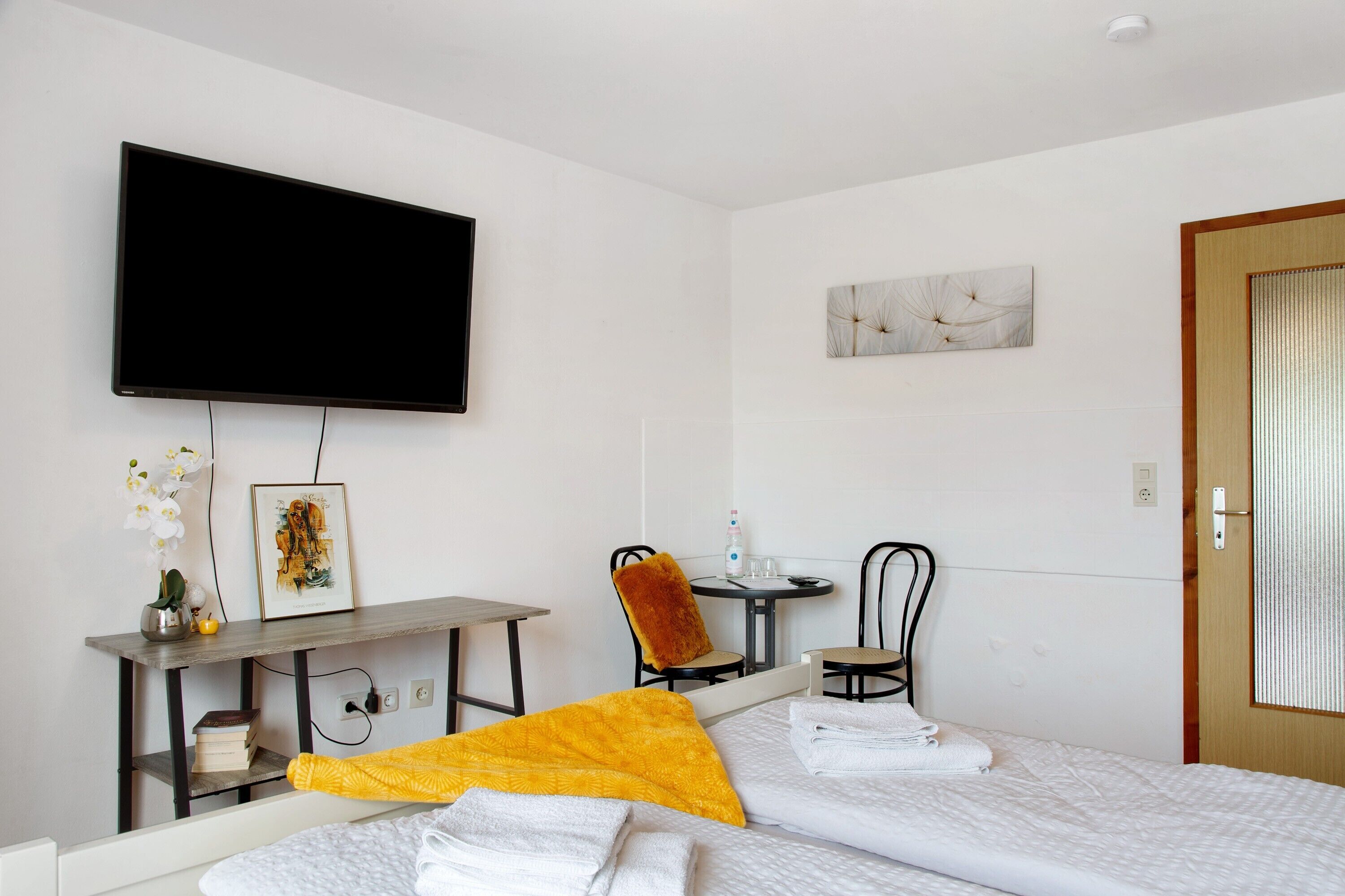 Une chambre d’hôtel comprenant un lit, un bureau avec une chaise, une télévision et une petite table avec une chaise.