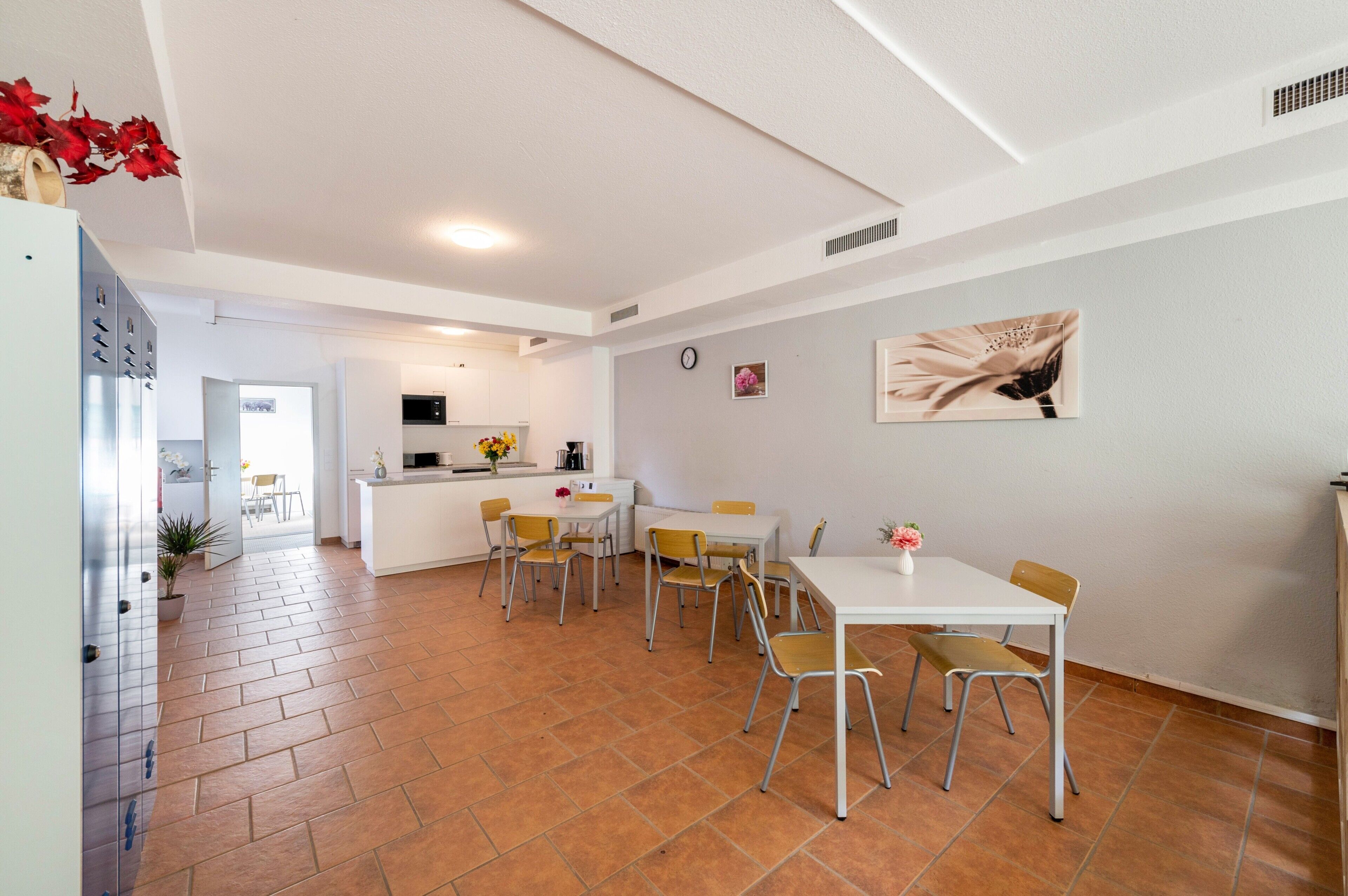 Una cocina moderna con armarios blancos, una zona de comedor con sillas amarillas y una mesa blanca.