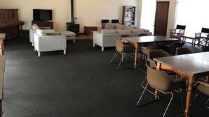 A spacious room with a large sofa set, a dining table with chairs, a television, and a bookshelf. - Gum Valley Quarters: perfect for large groups and families (Western River)