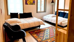 Un dormitorio con dos camas, una silla, un tapete y obras de arte en la pared.