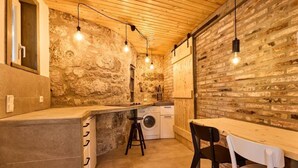 Una cocina rústica con paredes de ladrillo visto, techo de madera e iluminación colgante.