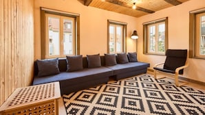 Una habitación con techo de madera, un sofá con cojines, una silla y un tapiz estampado.