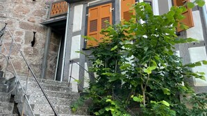 Un edificio histórico con paredes de piedra, contraventanas de madera y una escalera de metal.