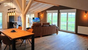 Een ruime loft met een houten eettafel, een bank en een televisie.
