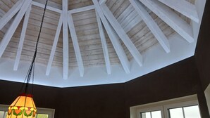 Een kamer met een schuine balken plafond en een hanglamp.
