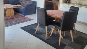 Un salon moderne comprenant un canapé, une table à manger avec des chaises, un coin cuisine et un petit balcon.