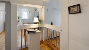 Een kamer met een houten vloer, witte muren, een wit kastje, een lamp en een kleine plant.