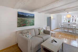 A living room with a sofa, a coffee table, a painting, and a dining area with chairs and a table. - Apartment 'Omi Anni' with a view of the market square, Private Terrace and Wi-Fi (Schlitz)