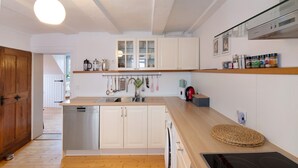 Een moderne keuken met witte kasten, een vaatwasser, een ingebouwde oven en een houten aanrecht.