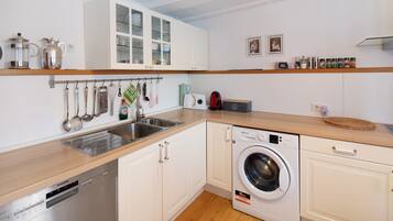 A modern kitchen with white cabinets, a dishwasher, a washing machine, and various kitchen utensils.