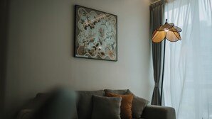 Un salon avec un canapé, une œuvre d’art accrochée au mur et une lampe sur pied.
