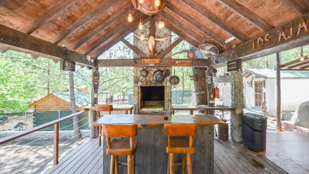 A rustic wooden bar area with a stone fireplace, wooden bar stools, and a sign reading 'Los Alamos.' - Constelation Cabin / for big groups, 18 people (La Ciénega de González)