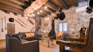 A cozy living room with a sofa, a coffee table, and a fireplace. There are skis and a bear head mounted on the wall. - Constelation Cabin / for big groups, 18 people (La Ciénega de González)