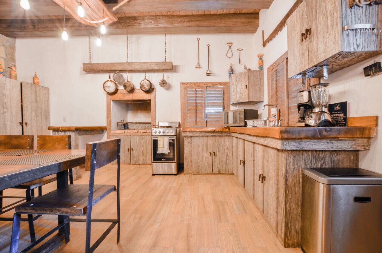 Una cocina con armarios de madera, estufa, lavabo y utensilios colgando.