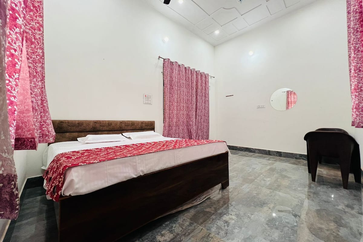 Un dormitorio con cama, una silla, un espejo e iluminación empotrada en el techo.