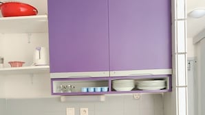 A modern kitchen with purple cabinets, a coffee maker, and a kettle on the counter.