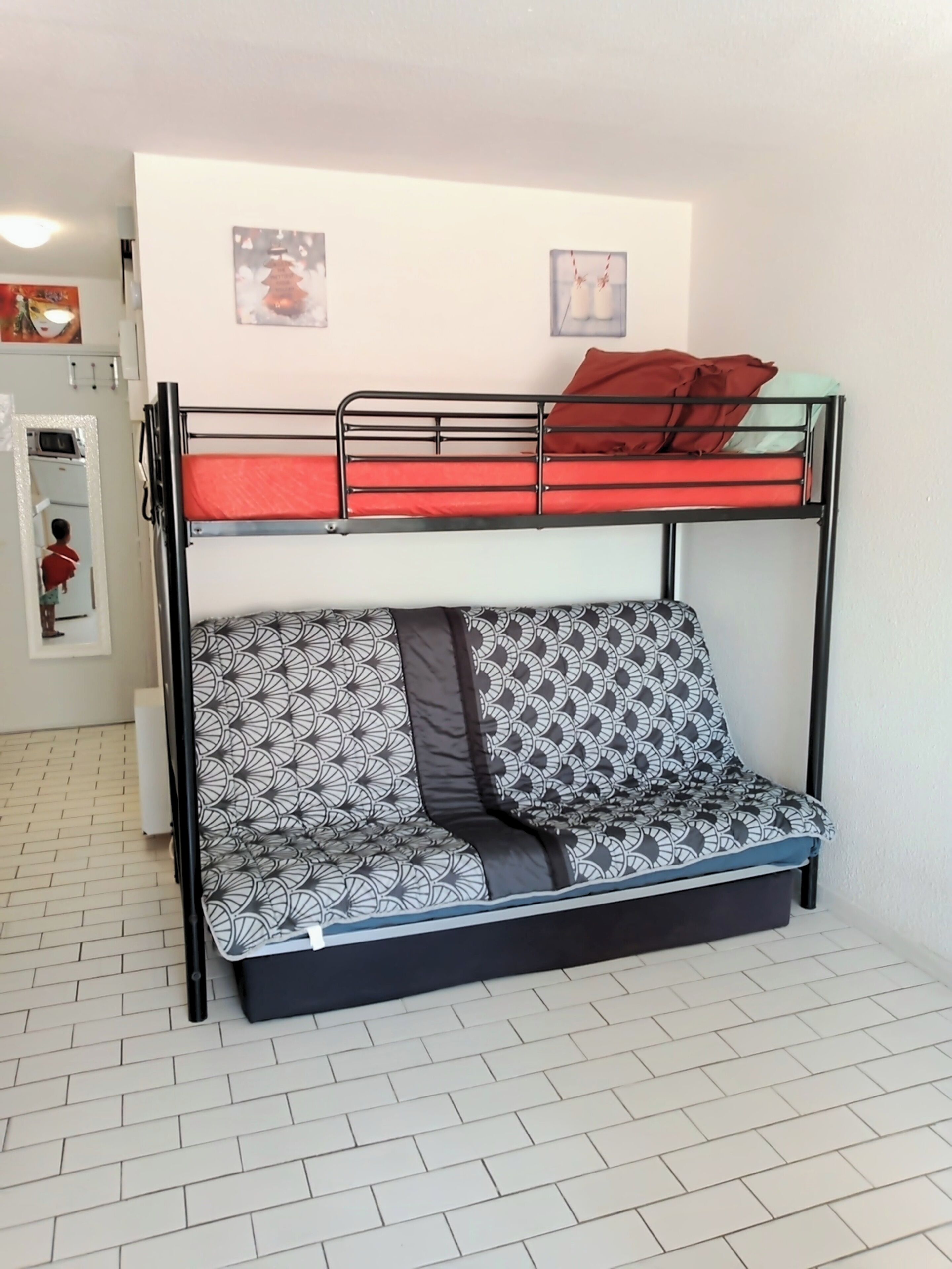 A bunk bed with a lower bunk featuring a patterned cushion and a mattress.