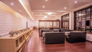 A spacious restaurant with a long counter, cushioned seating, and large windows. - Hotel Zomday (Leh)
