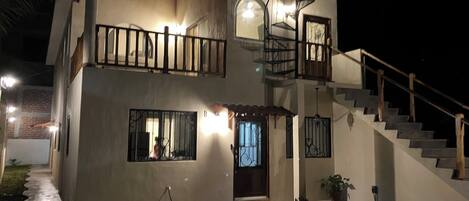 A two-story house with a balcony, a staircase, and a well-lit entrance.