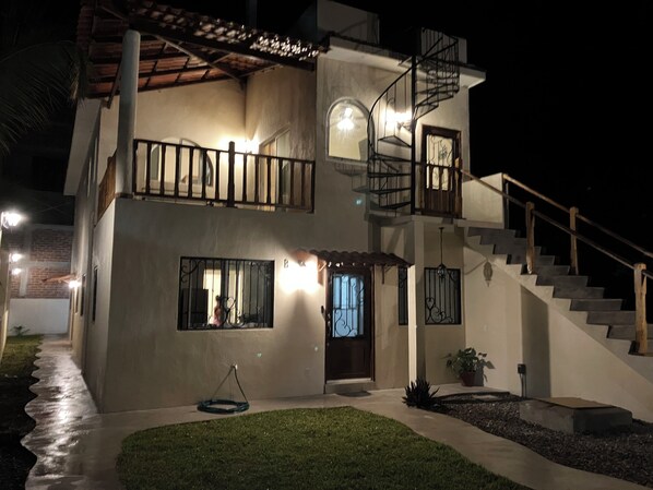 A two-story house with a balcony, a staircase, and a well-lit entrance.