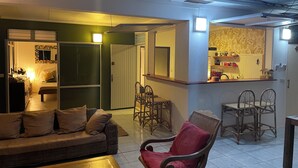A living room with a sofa, a red chair, a coffee table, and a dining area with chairs and a table.