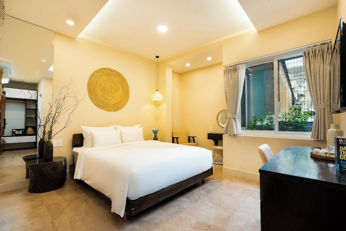 A modern bedroom with a large bed, a dining table, and a window with curtains.