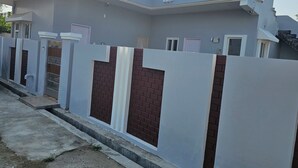 Una casa moderna de dos pisos con fachada gris, ventanas con marcos blancos y una pared de acento de ladrillo.