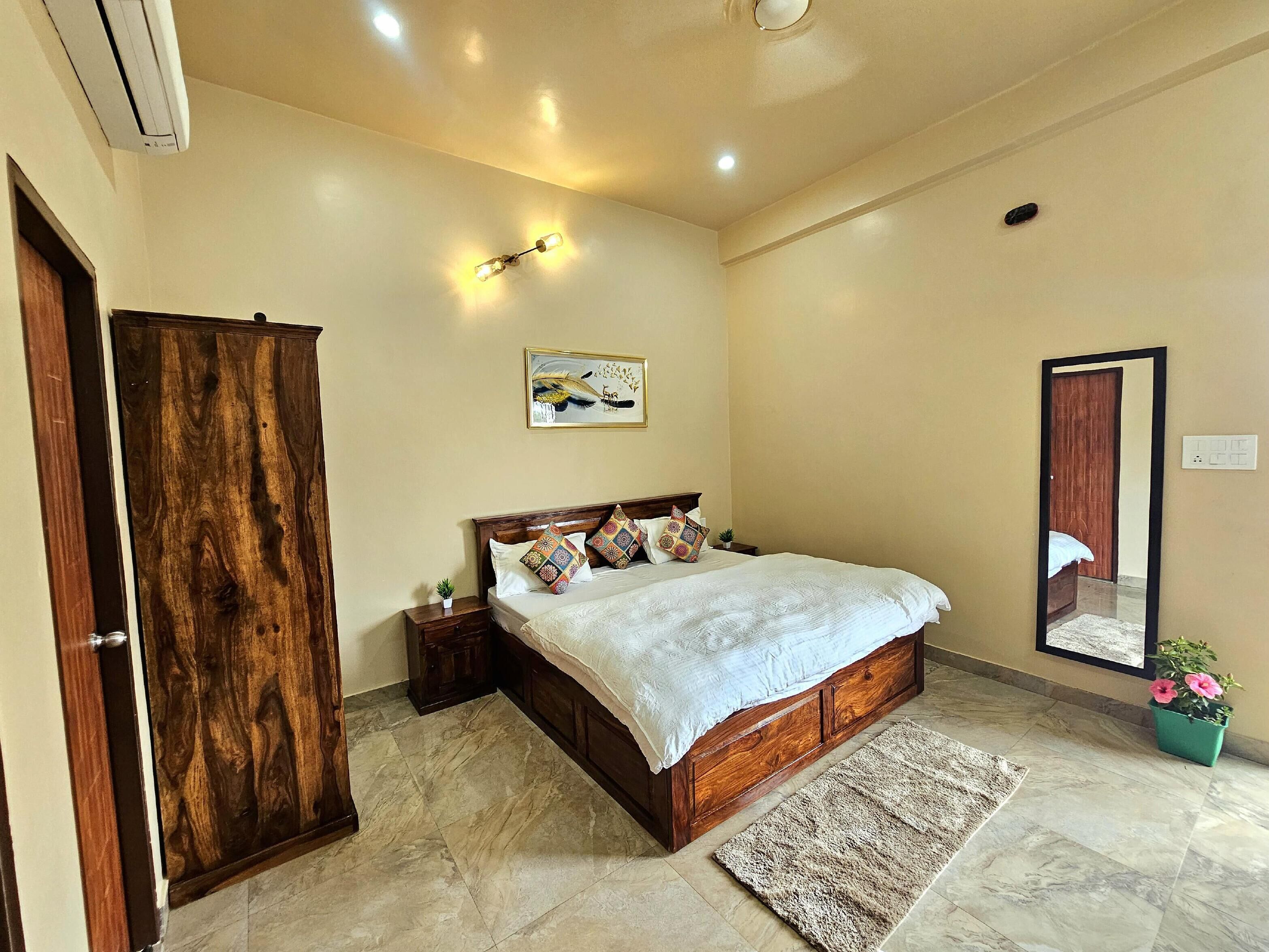 Un dormitorio con una cama de madera, una mesita de noche, un espejo, un aplique de pared y un cuadro.