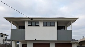 Ett tvåvåningshus med ett platt tak, två garageportar och en grusuppfart.