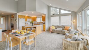 A spacious living area with a dining table, wicker chairs, and a sofa. - Ocean Views, Game Garage & Steps to Neahkahnie Beach | Bella Sol by AvantStay (Nehalem)