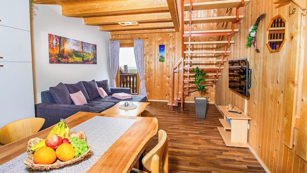 Un intérieur en bois comprenant un coin repas, un canapé, un escalier et un tableau au mur.