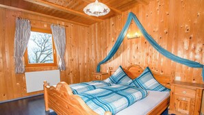 Une pièce en bois avec un lit, des rideaux, une table de chevet et une fenêtre.