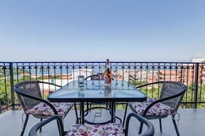 A balcony with a glass table and chairs, a bottle, and a glass. - MarBok Apartments with SeaView (Utjeha)